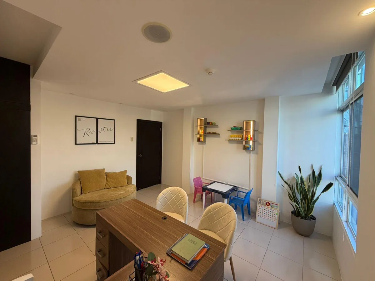 Consultorio de PsiqueMind con escritorio, sofá y rincón de juego para niños junto a la ventana.