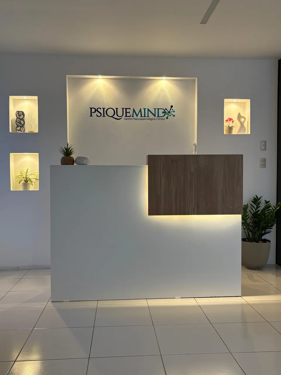 Recepción de PsiqueMind con el logotipo del Centro Neuropsicológico Clínico iluminado sobre la pared.