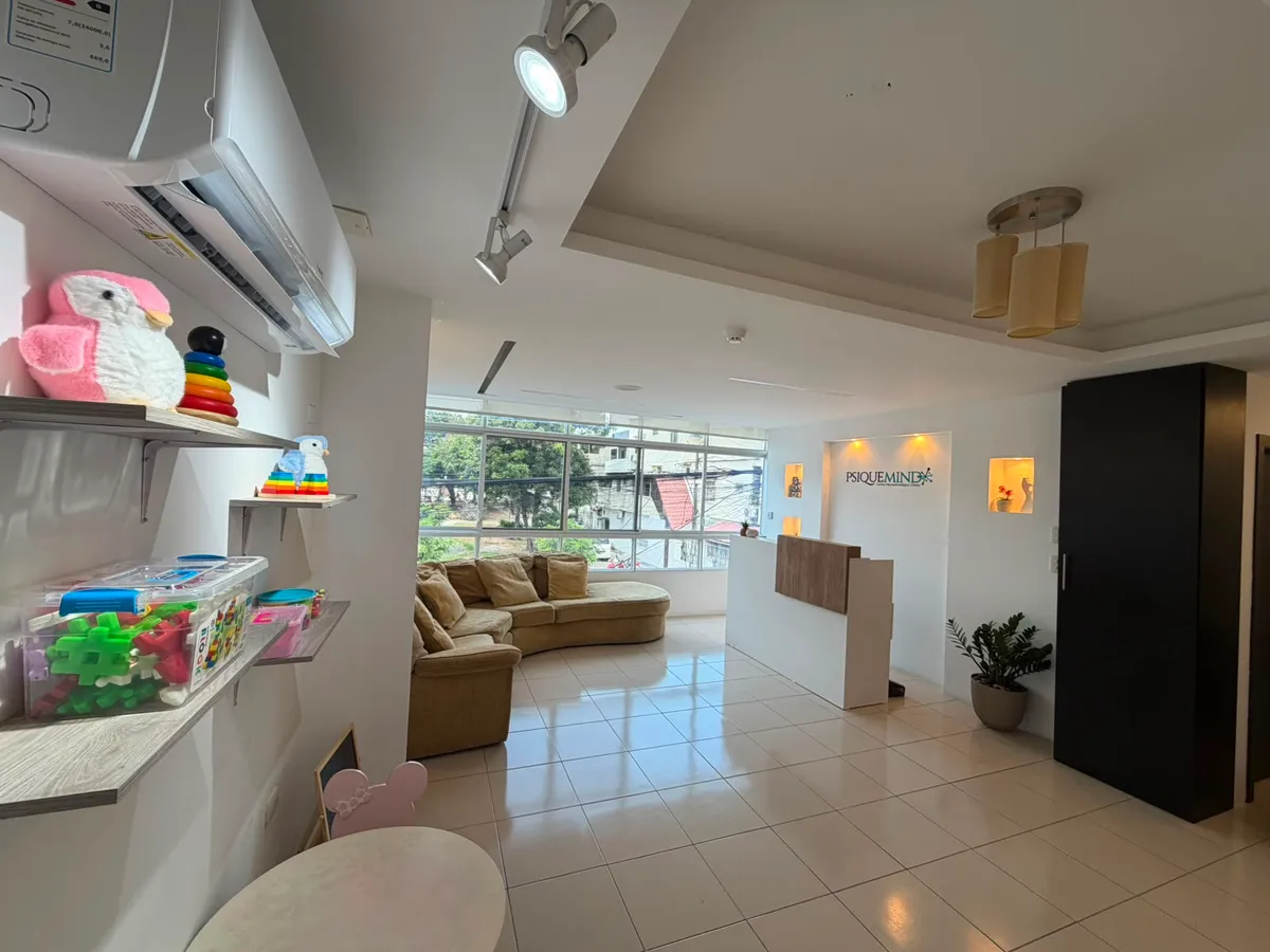 Sala de espera de PsiqueMind con el logo en la pared, sillón cómodo y luz natural.